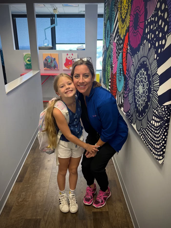 A pediatric dentist at Children’s Dental Specialists in Richardson, TX, performing a gentle dental exam on a young girl.