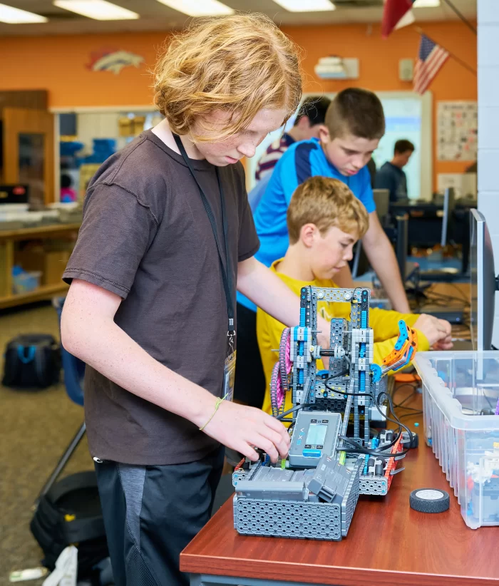 A group of middle school students working together to build and program a VEX robot in a STEM lab.