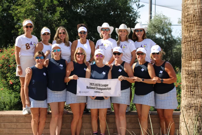Two women 55+ playing competitive doubles tennis, demonstrating communication and focus during a match.