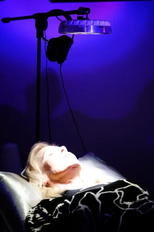 A client resting on a Vibe Bed with a Roxiva light therapy panel positioned above them for nervous system regulation.