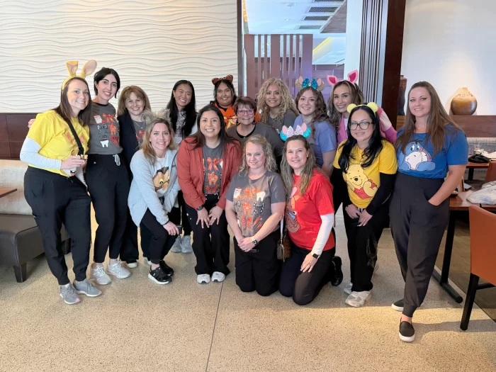 The full staff of Children’s Dental Specialists, including assistants and hygienists, wearing fun character-themed shirts for a team photo.