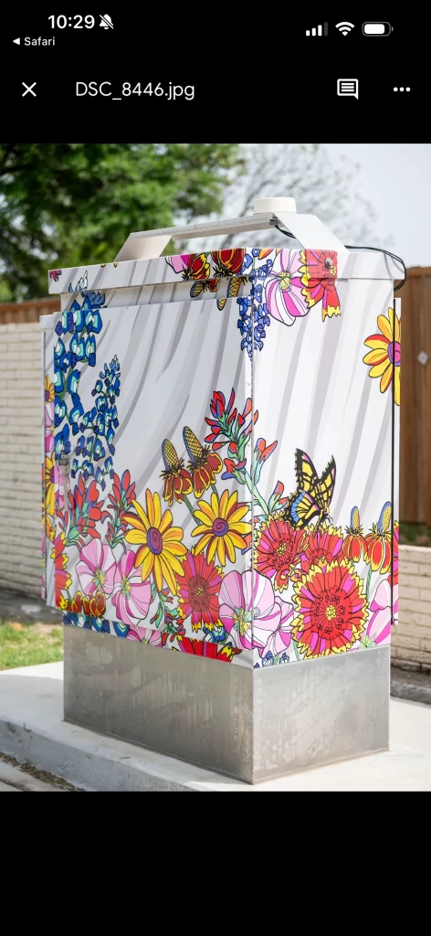 A traffic signal utility box on a Richardson street corner wrapped in colorful vinyl art featuring a vibrant, stylized floral design.