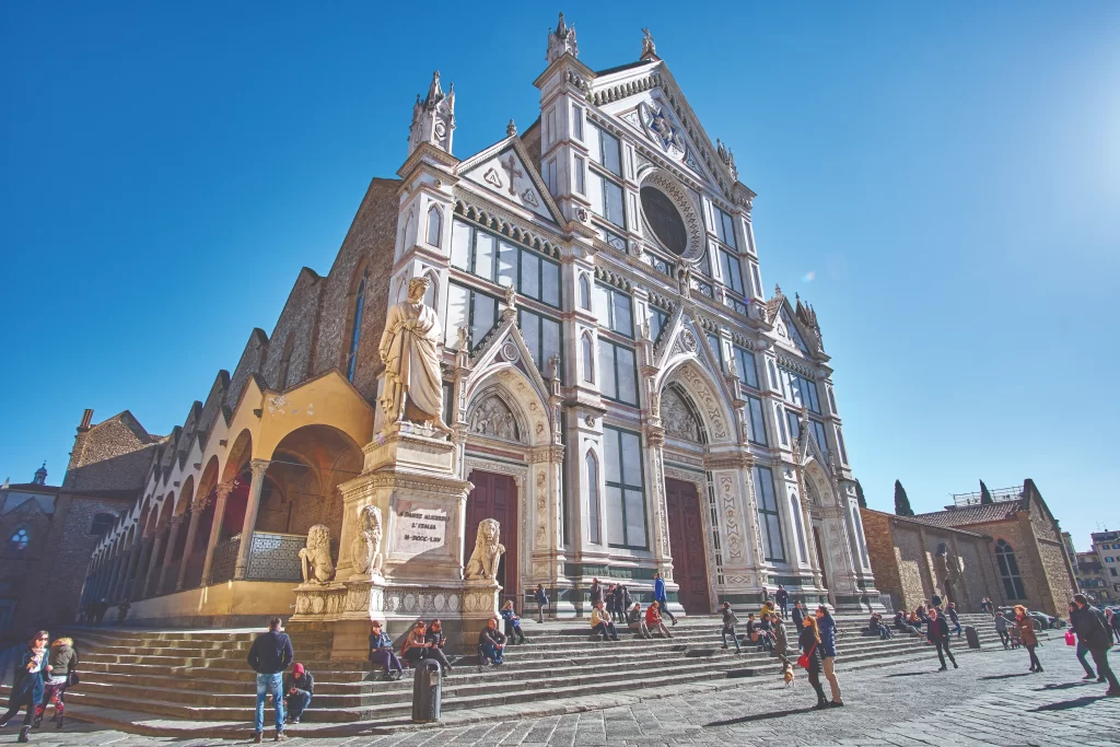 A scenic view of the Ponte Vecchio in Florence at sunset, with the colorful medieval stone bridge reflecting in the Arno River.