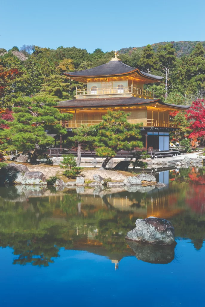 The Kinkaku-ji (Golden Pavilion) in Kyoto, a Zen Buddhist temple with its top two stories completely covered in gold leaf, reflecting in the mirror pond surrounded by pine trees.