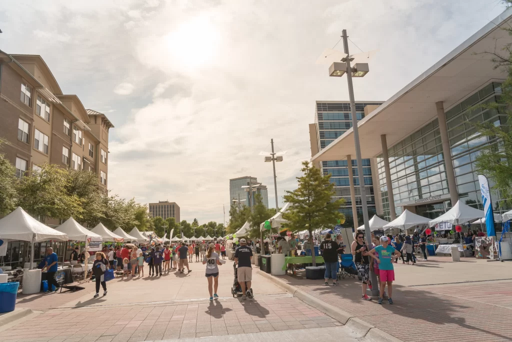 Crowds explore vendor tents and exhibits during a community festival near the Eisemann Center in Richardson, Texas.
