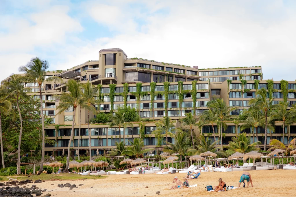 Beachfront resort surrounded by palm trees overlooking a sandy shoreline on Kauai's North Shore.