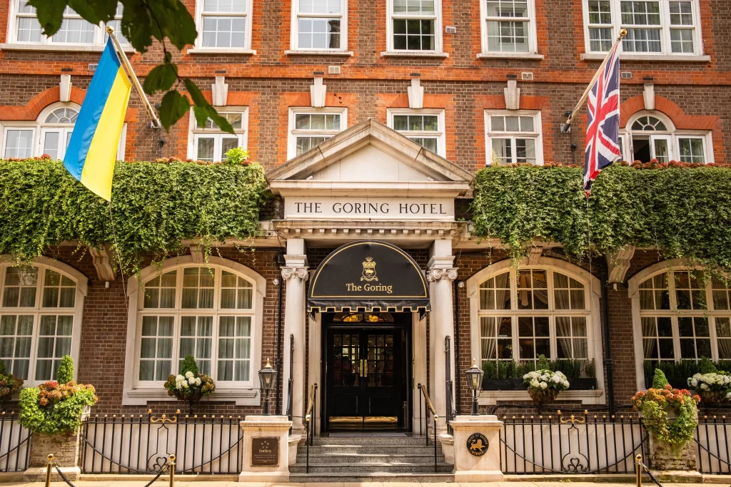 Front entrance of The Goring Hotel in London featuring historic brick architecture, ivy-covered balconies, and national flags.