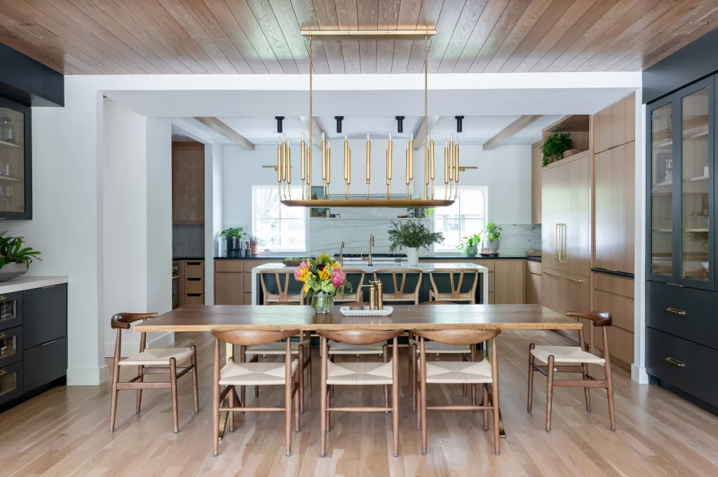 Open-concept kitchen and dining area with wood ceiling, large island, natural wood cabinetry, and statement pendant lighting.